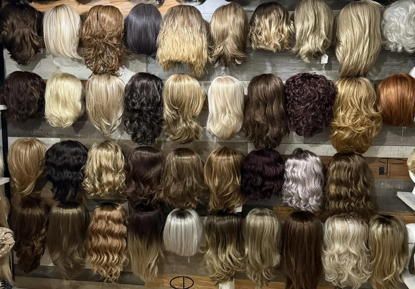 Rows of wigs and hairpieces in every shade hanging on the salon wall