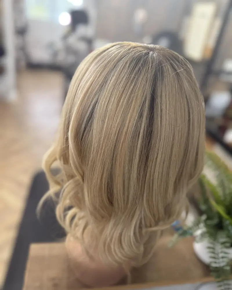 Blonde wavy wig on a stand, back view